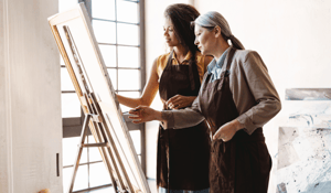 Teacher and artist conversing in front of easel